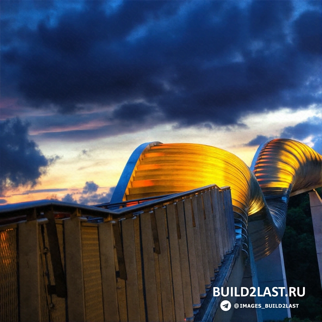 Золотистый пешеходный мост в Сингапуре с плавными изгибами, освещённый солнечным светом.